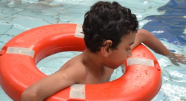 criança na piscina apoiada em uma bóia