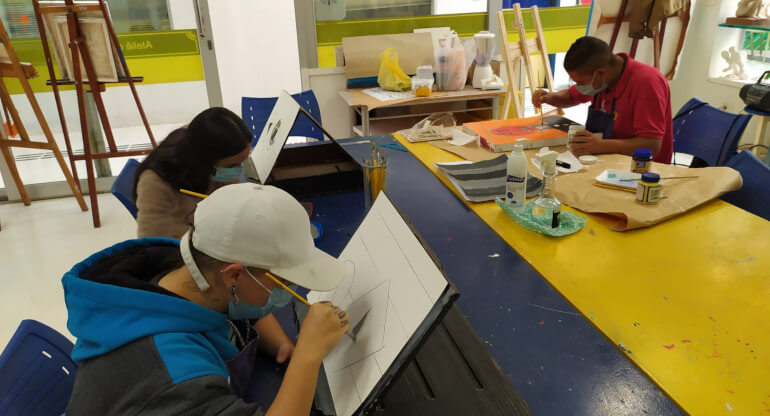 Aula do curso de desenho e pintura da Laramara. Na foto há três alunos desenhando em tela