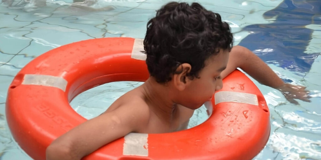 criança na piscina apoiada em uma boia